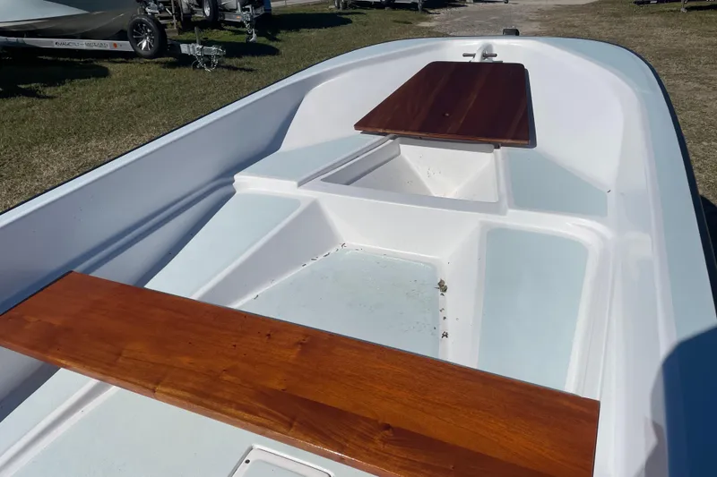 Slide: The Image of 1985 Boston Whaler 15' boat interior with wooden seats, parked on grass. - 7