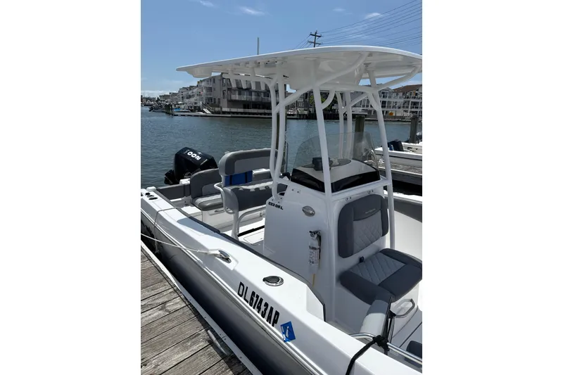 Slide: The Image of 2024 NauticStar 222L Offshore boat docked by waterfront homes. - 3