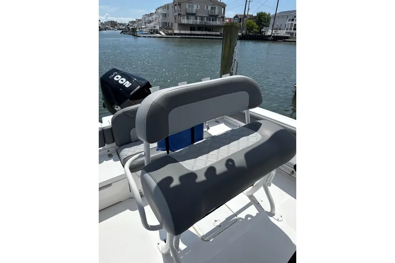 Slide: The Image of 2024 NauticStar 222L Offshore boat with gray seating, docked by waterfront homes. - 6