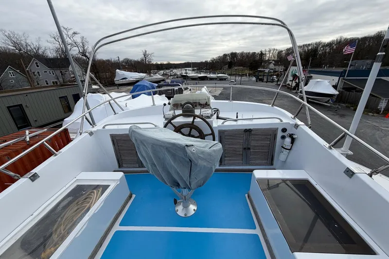 Slide: The Image of 1984 Golden Star 38 Trawler helm with covered seat, docked in a marina. - 16