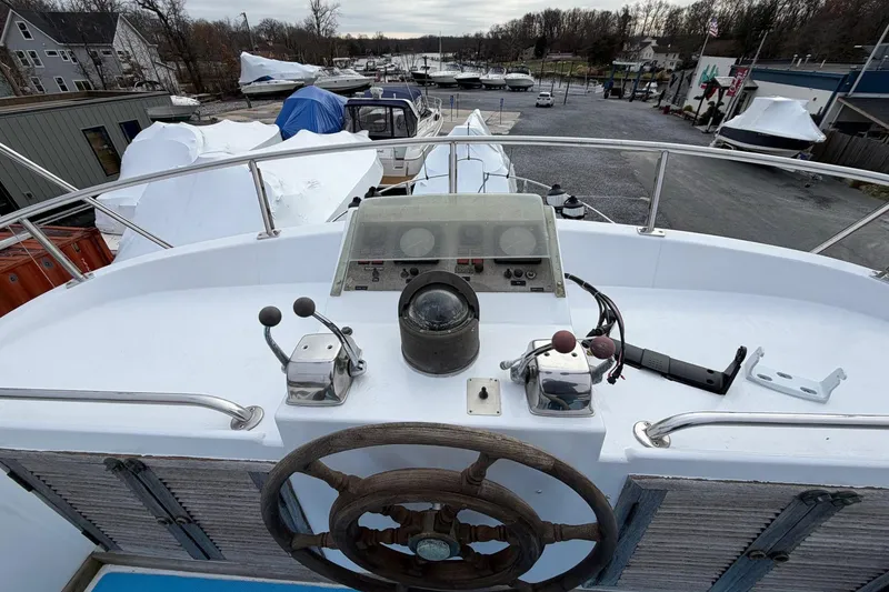 Slide: The Image of 1984 Golden Star 38 Trawler helm with wooden wheel and control panel, docked in a marina. - 18