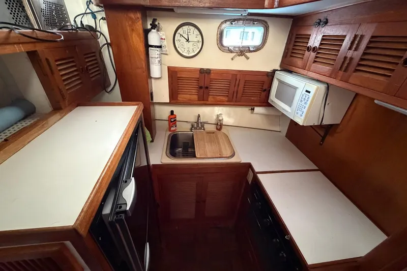 Slide: The Image of 1984 Golden Star 38 Trawler kitchen with wooden cabinets, sink, and microwave. - 31