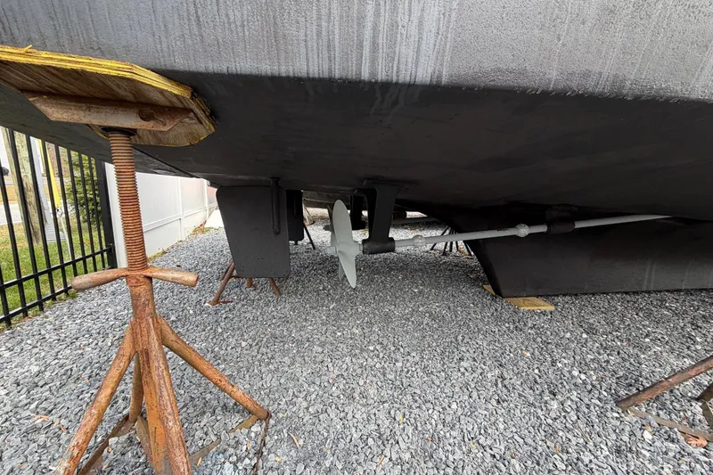 Slide: The Image of Underneath view of a 1984 Golden Star 38 Trawler on gravel, showing propeller and supports. - 7