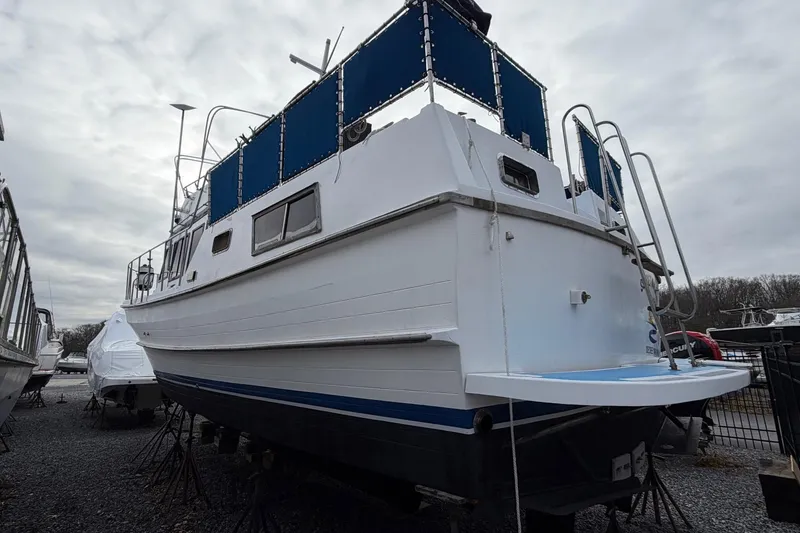 Slide: The Image of 1984 Golden Star 38 Trawler with blue accents, docked on gravel under cloudy skies. - 9