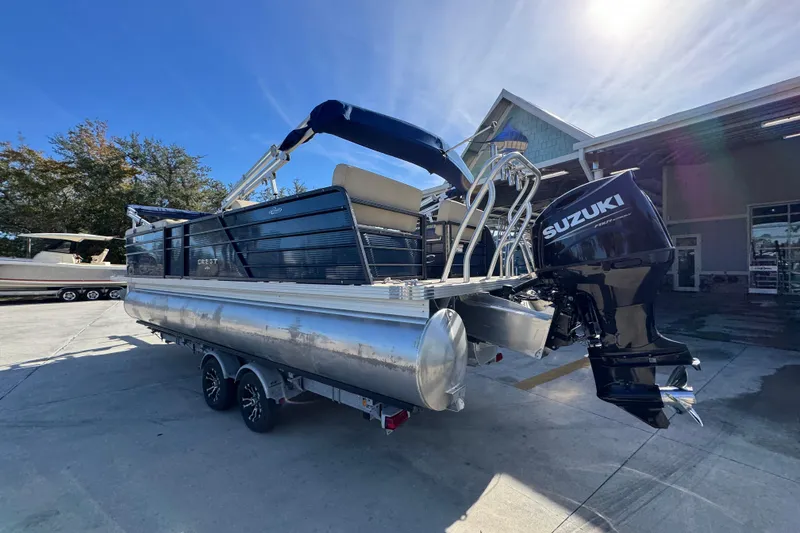 Slide: The Image of 2022 Crest Classic LX 240 SLRC pontoon boat with Suzuki outboard motor in a sunny marina. - 18