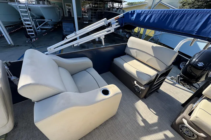 Slide: The Image of 2022 Crest Classic LX 240 SLRC boat interior with beige seating and blue canopy. - 33