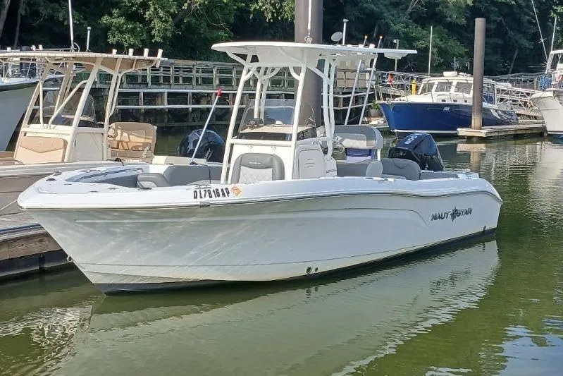 The Image of 2024 NauticStar 222L Offshore boat docked in a marina, surrounded by other vessels. - 1
