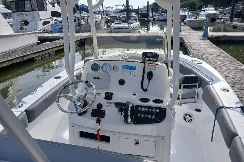 Slide: The Image of 2024 NauticStar 222L Offshore boat dashboard at marina, featuring modern controls and steering. - 3