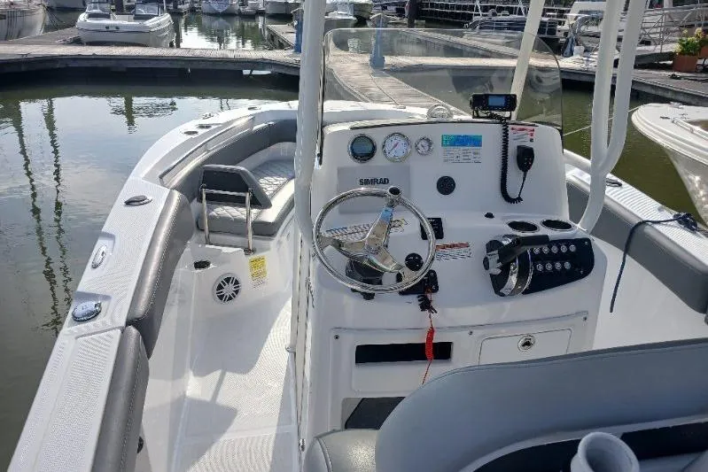 Slide: The Image of 2024 NauticStar 222L Offshore boat interior with steering console at marina. - 4