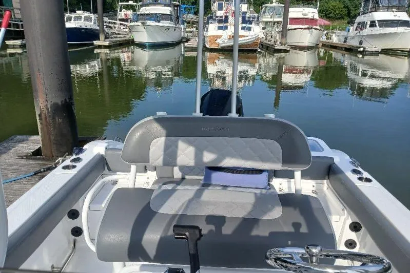 Slide: The Image of 2024 NauticStar 222L Offshore boat interior at marina with docked boats. - 6