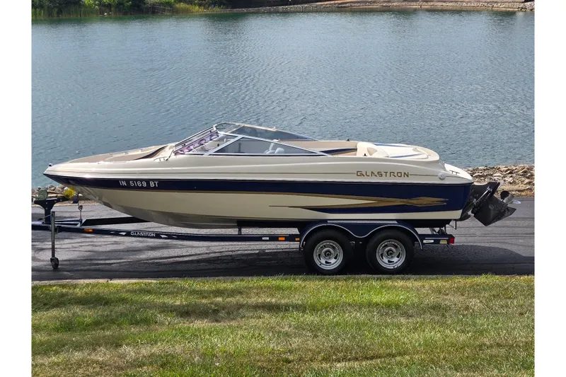 The Image of 2001 Glastron GX 205 boat on trailer by a lake, side view. - 0