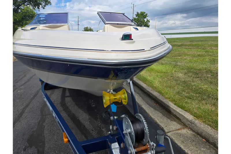 Slide: The Image of 2001 Glastron GX 205 boat on trailer, parked on asphalt near grass. - 6