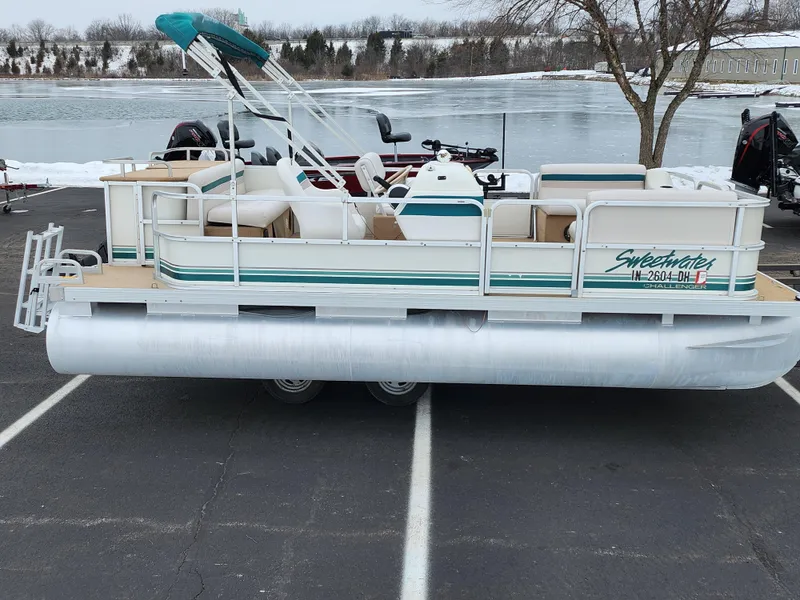 Slide: The Image of Sweetwater 180 pontoon boat, 2000 model, parked near a lake in winter setting. - 0