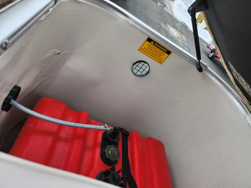 Slide: The Image of Storage compartment of a 2000 Sweetwater 180 boat with red fuel tank and warning label. - 14