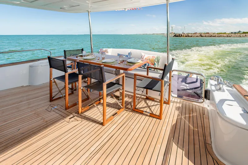 Slide: The Image of Luxurious 2023 Sirena 58 yacht deck with dining area, overlooking serene ocean waters. - 14