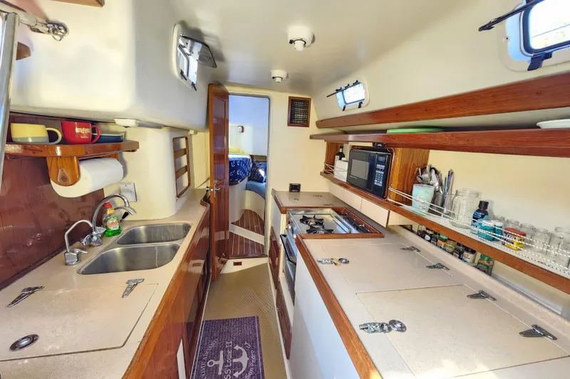 Slide: The Image of 1994 Catalina Morgan 38 yacht interior kitchen with sink, stove, and wooden shelves. - 20