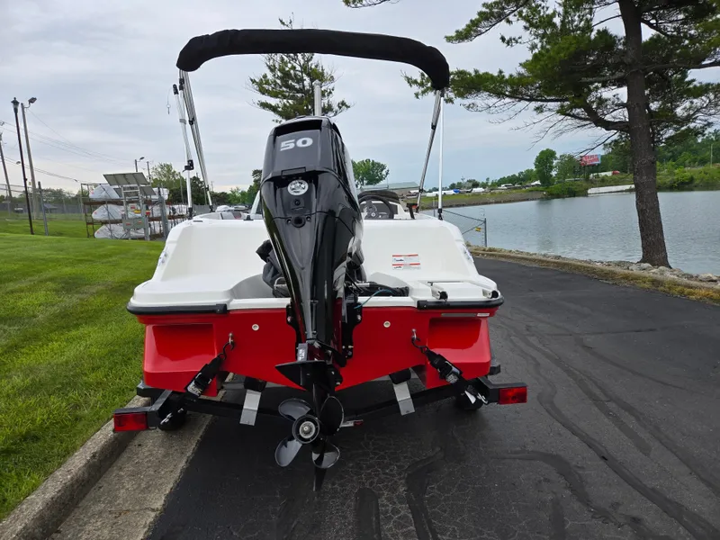 Slide: The Image of 2022 Bayliner Element M15 boat with outboard motor, parked near a lakeside. - 2