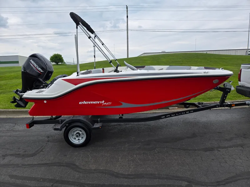 Slide: The Image of 2022 Bayliner Element M15 boat in vibrant red on a trailer, parked outdoors. - 4