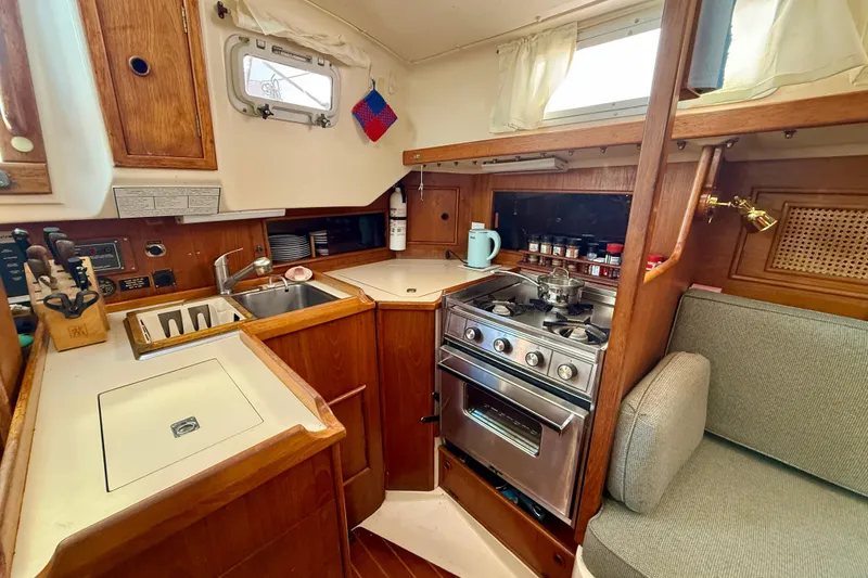 Slide: The Image of Compact 1985 Niagara Encore yacht kitchen with stove, sink, and wooden cabinetry. - 12