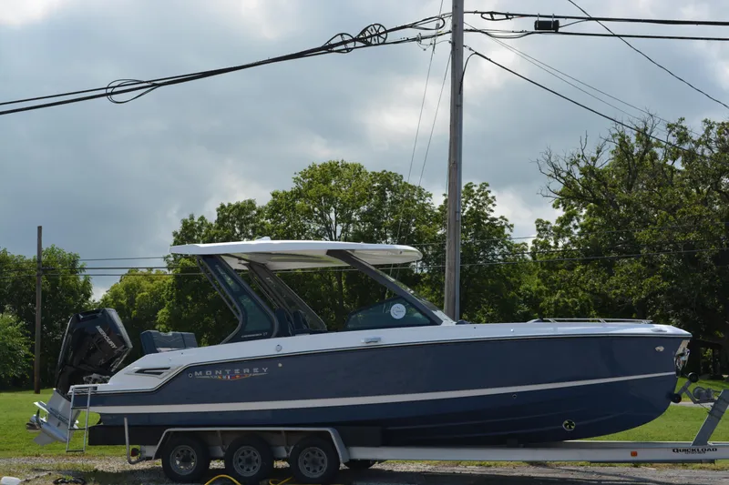 Slide: The Image of 2026 Monterey Elite 27 OB boat on trailer, parked outdoors under cloudy sky. - 2