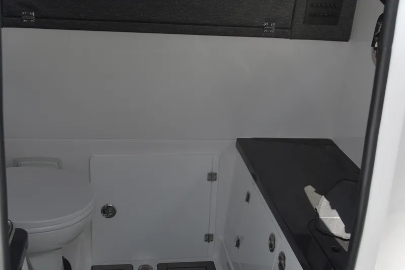 Slide: The Image of Interior of 2026 Monterey Elite 27 OB boat, featuring a compact bathroom with toilet and storage. - 24
