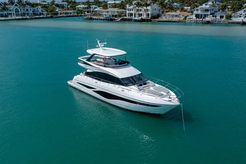 The Image of Luxurious 2026 Princess F65 yacht cruising in turquoise waters near coastal homes. - 0