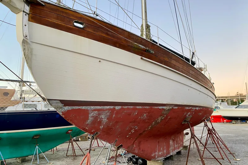 Slide: The Image of 1991 Hans Christian 41 T Molakai sailboat on dry dock, showing weathered hull and wooden details. - 11