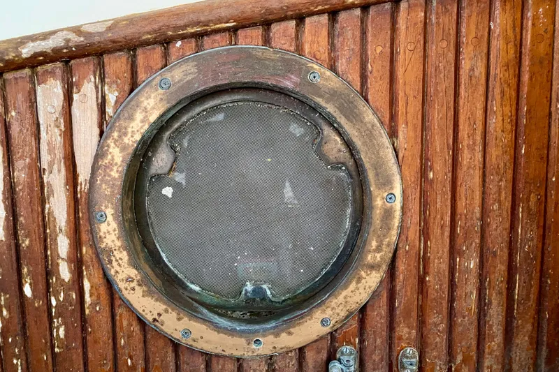 Slide: The Image of Weathered porthole on 1991 Hans Christian 41 T Molakai sailboat, surrounded by aged wooden paneling. - 68