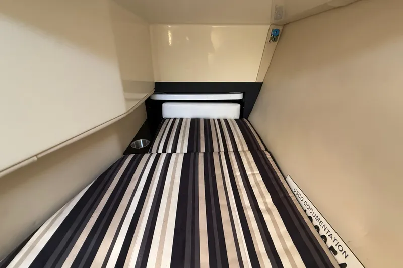 Slide: The Image of 2014 Monterey 328SS Super Sport cabin interior with striped bedding and storage space. - 48