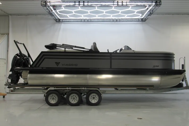 The Image of 2026 Viaggio Lago X22U pontoon boat on trailer in showroom with modern lighting. - 0