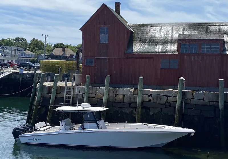 Slide: The Image of A white boat is docked at a wooden pier in front of a red building. - 8