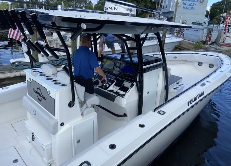 Slide: The Image of A 2021 Fountain 38 Tournament Edition boat docked. A man stands at the helm. - 6