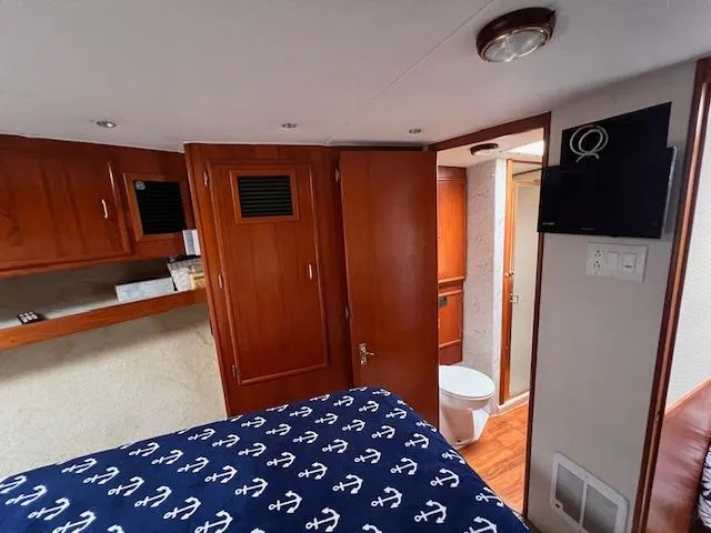 Slide: The Image of 1985 Post 43 Convertible cabin interior with wooden finishes and nautical-themed bedding. - 21