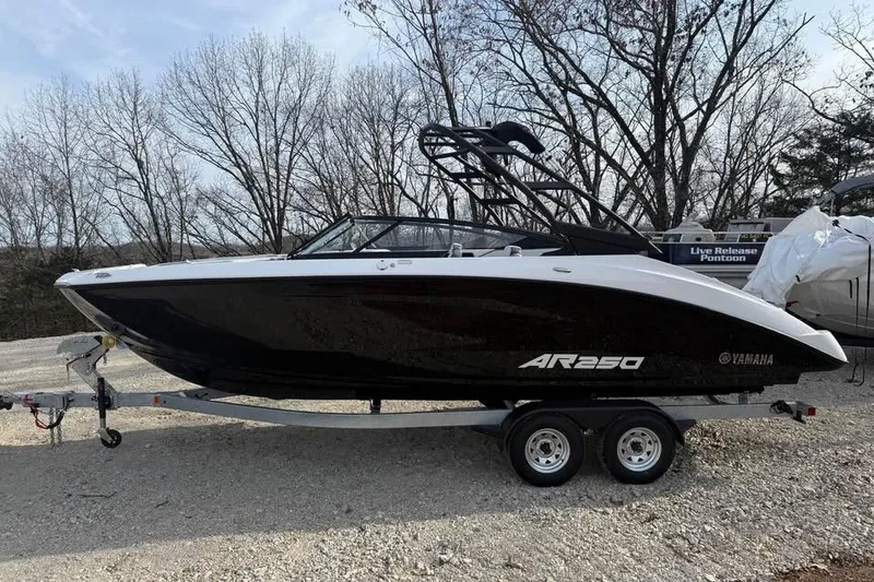 The Image of 2026 Yamaha Boats AR250 on trailer, parked outdoors with trees in background. - 0