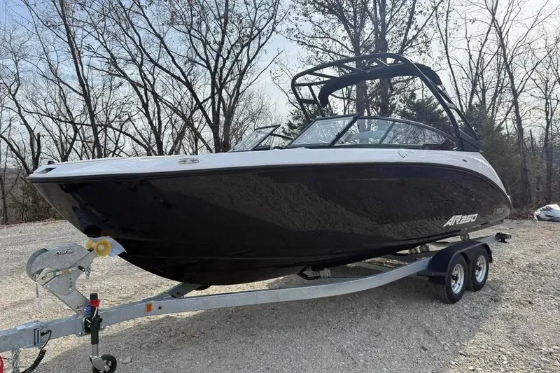 Slide: The Image of 2026 Yamaha Boats AR250 on trailer, parked outdoors with trees in background. - 1