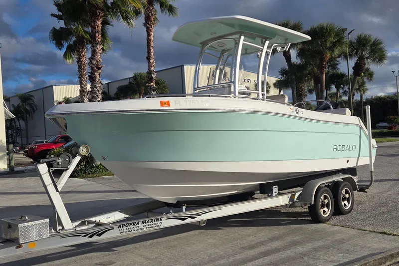 Slide: The Image of 2016 Robalo R222 Center Console boat on trailer, parked near palm trees. - 3