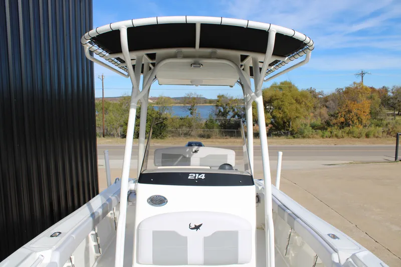 Slide: The Image of 2025 Mako 214 Center Console boat with T-top, parked near a scenic lake view. - 12