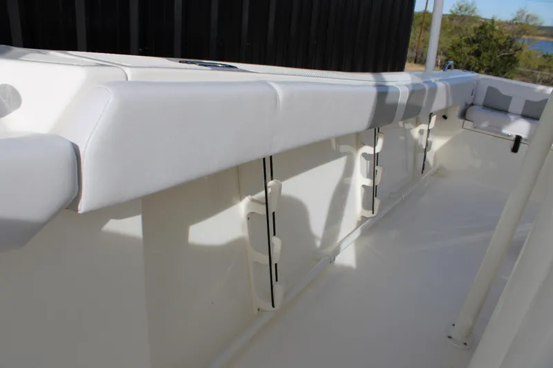 Slide: The Image of 2025 Mako 214 Center Console boat interior with white cushioned seating and rod holders. - 18