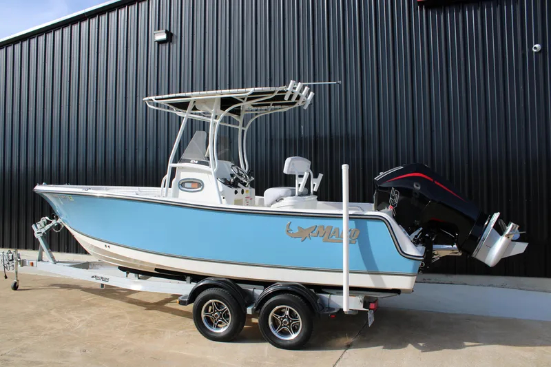 Slide: The Image of 2025 Mako 214 Center Console boat on trailer, blue hull, parked outdoors. - 5