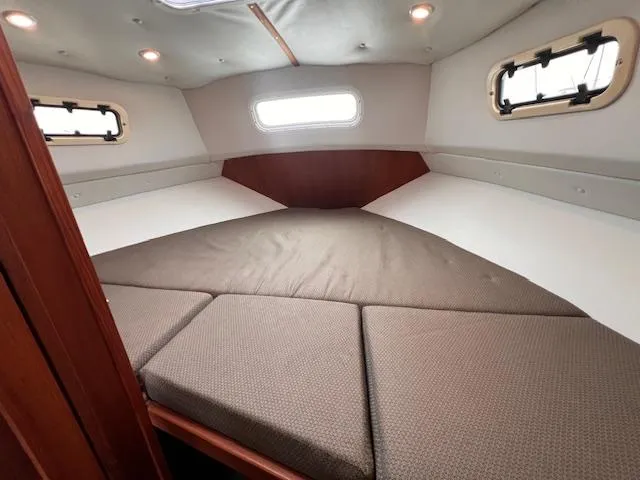 Slide: The Image of Interior cabin of 2004 Sea Sport Voyager 3000 with cushioned bed and porthole windows. - 20