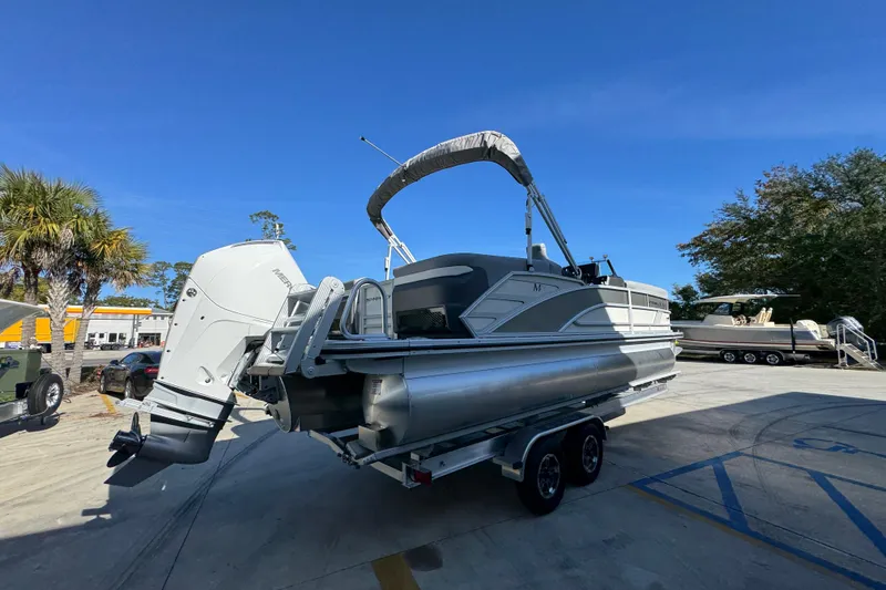 Slide: The Image of 2026 Bennington 24 MFB pontoon boat on trailer, parked outdoors under clear blue sky. - 12