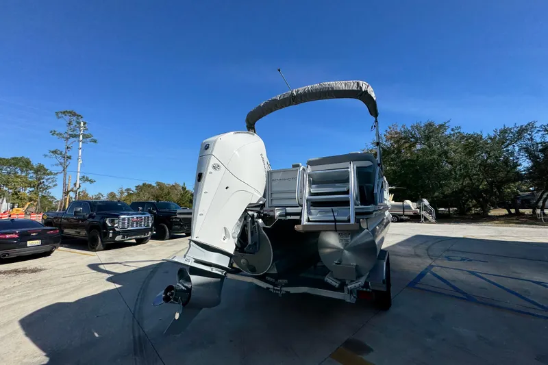 Slide: The Image of 2026 Bennington 24 MFB pontoon boat on trailer, parked outdoors under clear blue sky. - 13