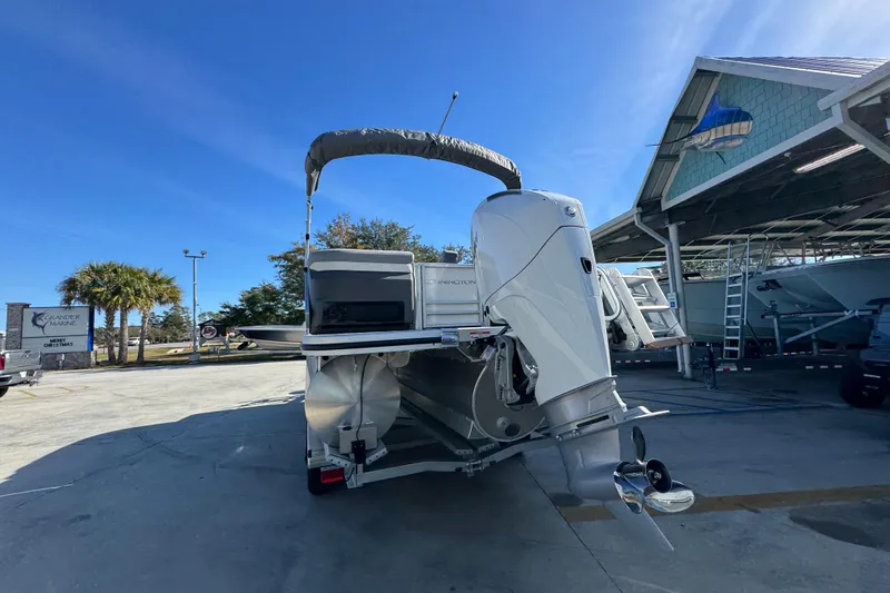 Slide: The Image of 2026 Bennington 24 MFB boat with outboard motor in a marina setting. - 15