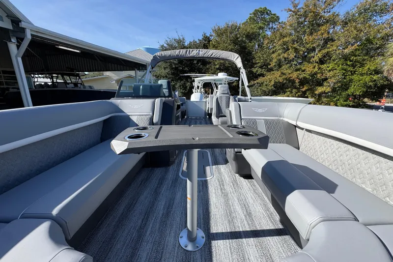 Slide: The Image of 2026 Bennington 24 MFB pontoon boat interior with gray seating and table, docked outdoors. - 19