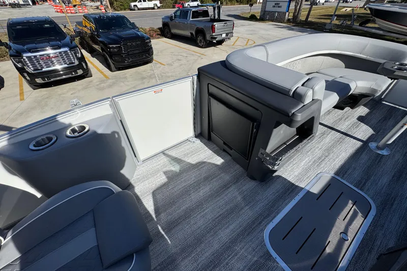 Slide: The Image of 2026 Bennington 24 MFB pontoon boat interior with seating and storage, parked near trucks. - 29