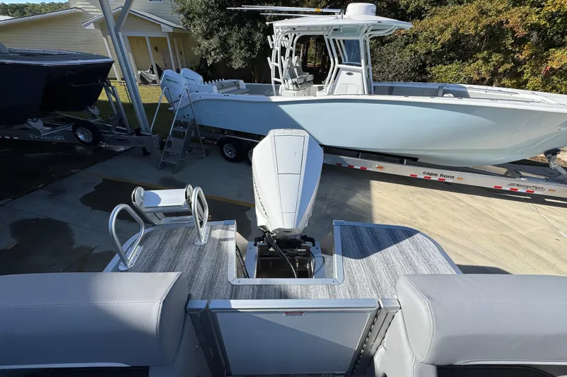 Slide: The Image of 2026 Bennington 24 MFB pontoon boat with outboard motor in a driveway setting. - 35