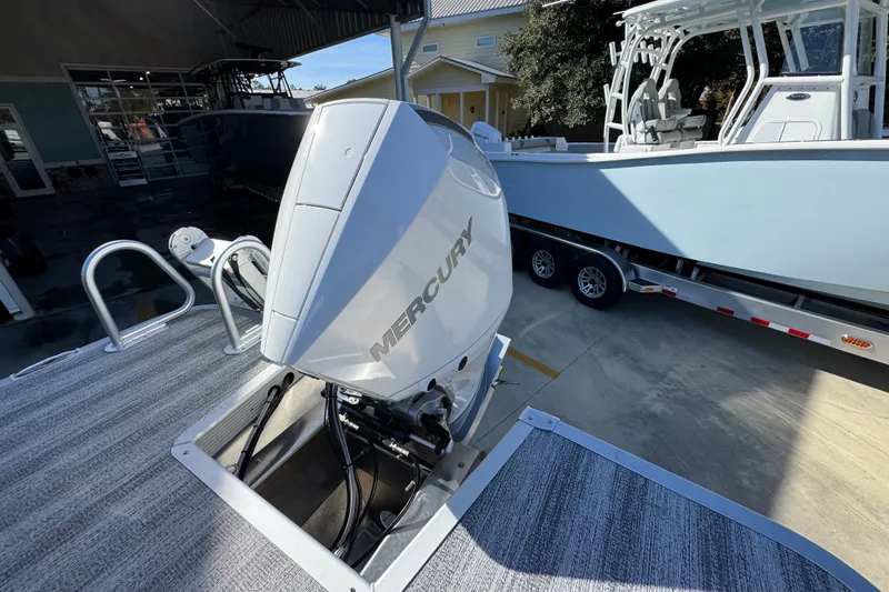 Slide: The Image of 2026 Bennington 24 MFB with Mercury outboard engine, parked near a trailer boat. - 36