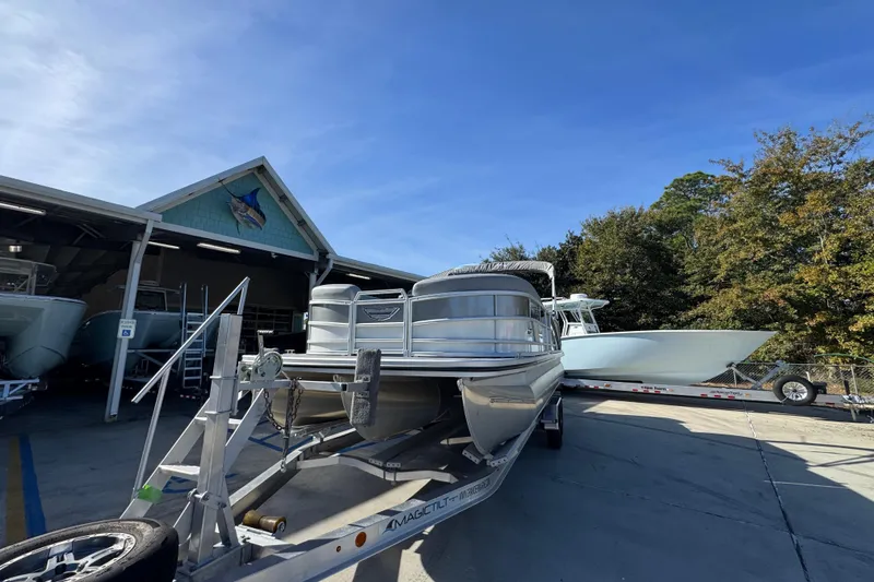 Slide: The Image of 2026 Bennington 24 MFB pontoon boat on trailer at marina under clear blue sky. - 5