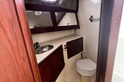 Slide: The Image of 2001 Carolina Classic 28 boat bathroom with sink, toilet, and wooden cabinets. - 10