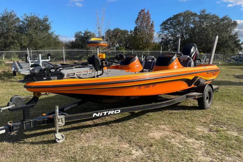 Slide: The Image of Orange 2008 Nitro Z-7 boat on trailer, parked on grass with trees in background. - 2